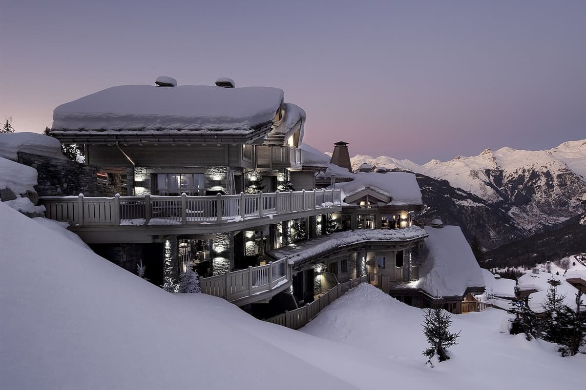 Verschneites Luxus-Chalet über den Pisten in der Abenddämmerung